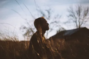 silhouette of man sitting on grass field at daytime